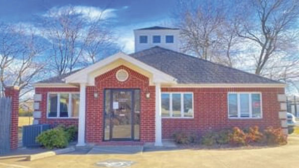 Waldrop Chiropractic building with a white entrance and columns, under a clear blue sky.