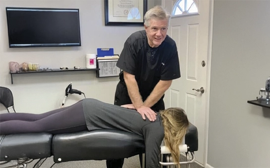 Dr. Craig Waldrop performing a spinal adjustment on a female patient lying face-down.